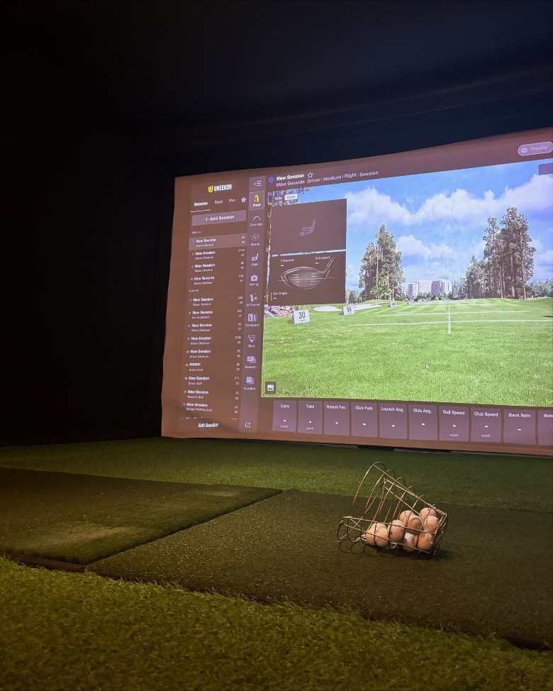 an indoor golf simulator and a basket of golf balls
