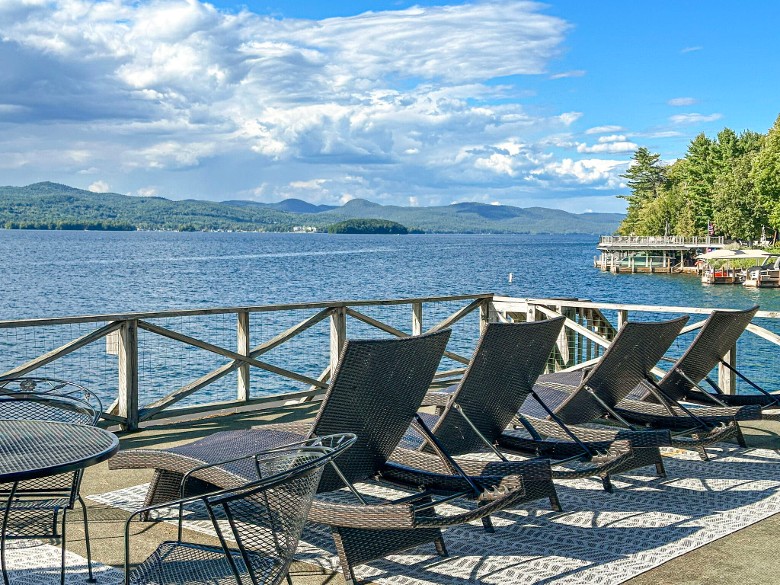 an outdoor deck with chairs overlooking a lake