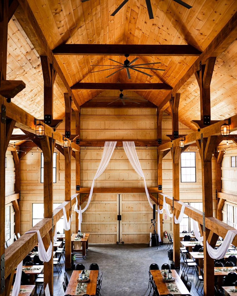 inside of a rustic barn wedding venue with tables and seating
