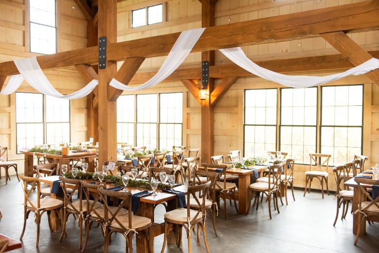 inside of a rustic barn wedding venue with tables and seating