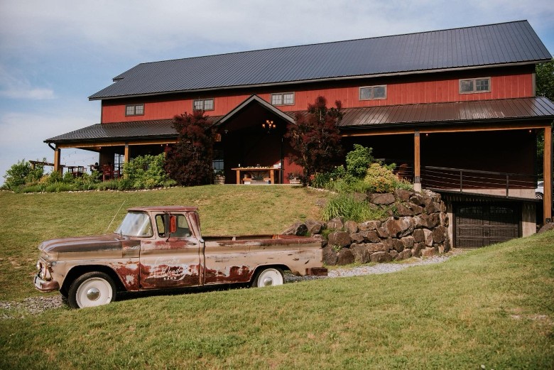 a red barn wedding venue with an antique truck outside