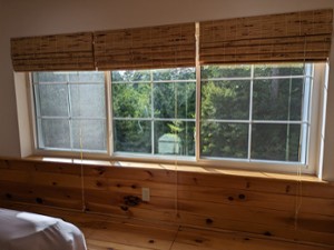 three windows in a bedroom with wooden walls