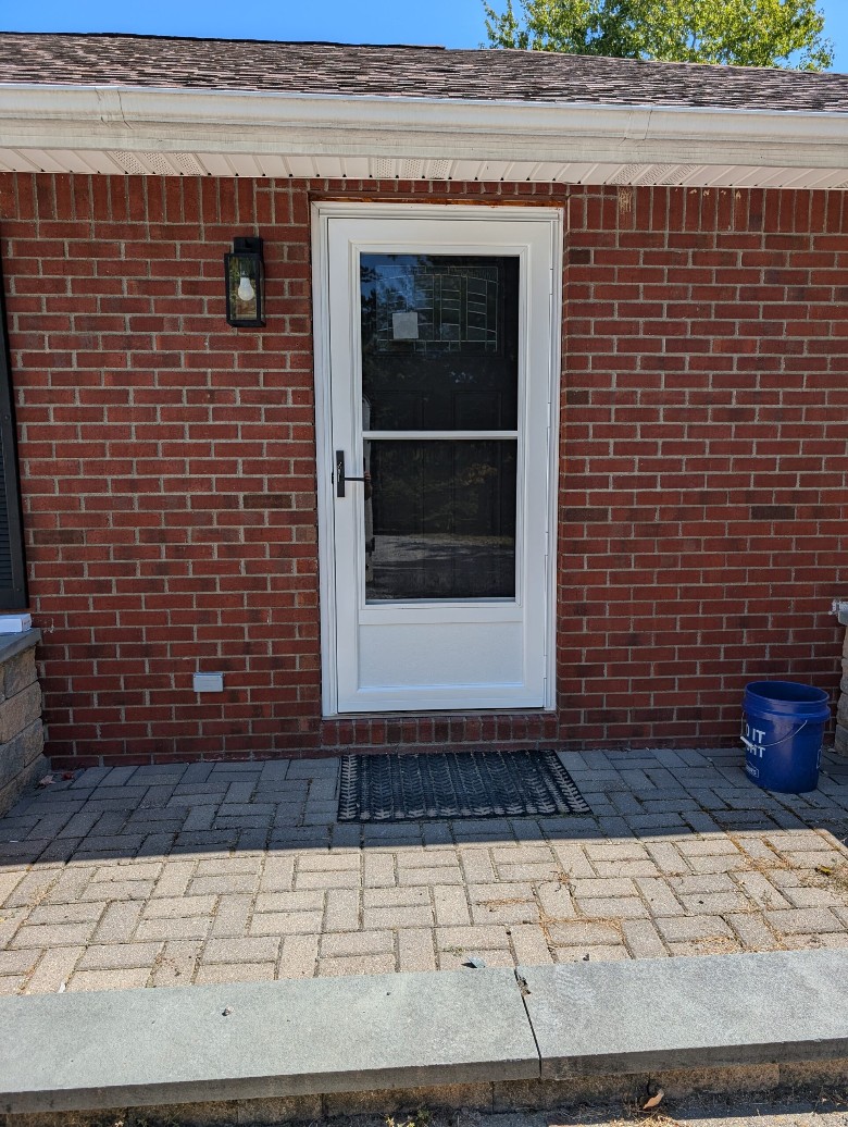a white door installed into a brick home