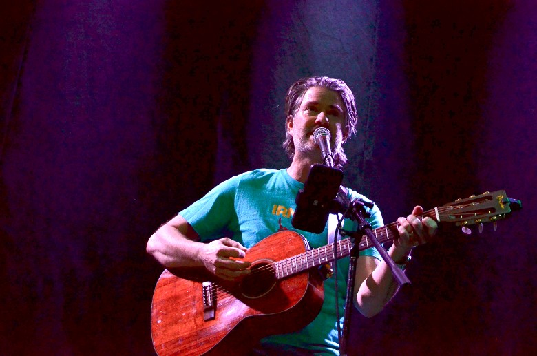 a man singing at a mic and playing a guitar