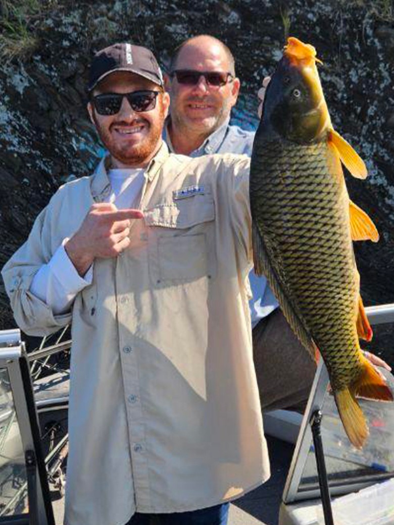 a man holding up a large fish on a boat