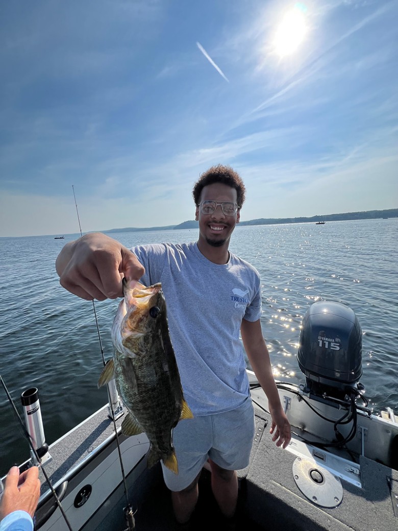 a man holding up a medium sized fish on a boat