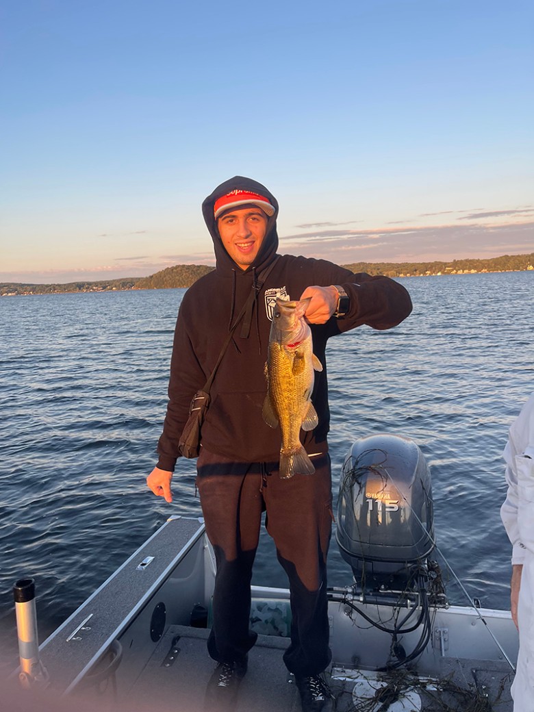 a man holding up a medium sized fish on a boat