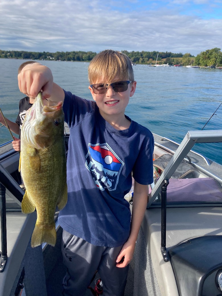 a boy holding up a fish on a boat