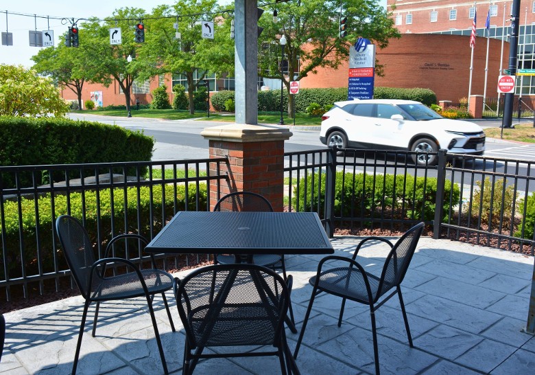 a restaurant patio with a table and chairs, and a black fence