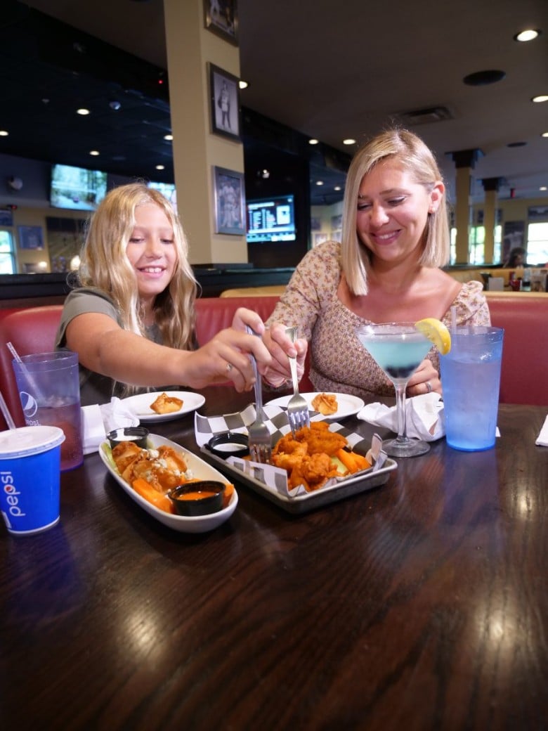 a mother and daughter eating boneless wings at a table
