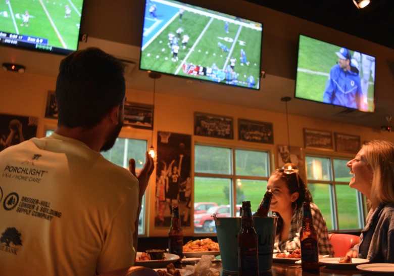 a man and two women watching football on TV in a sports bar