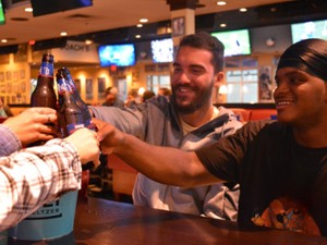 a group of men cheersing with beers in a sports bar