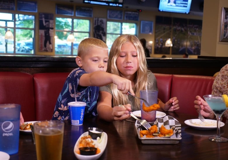 a boy and girl eating boneless wings