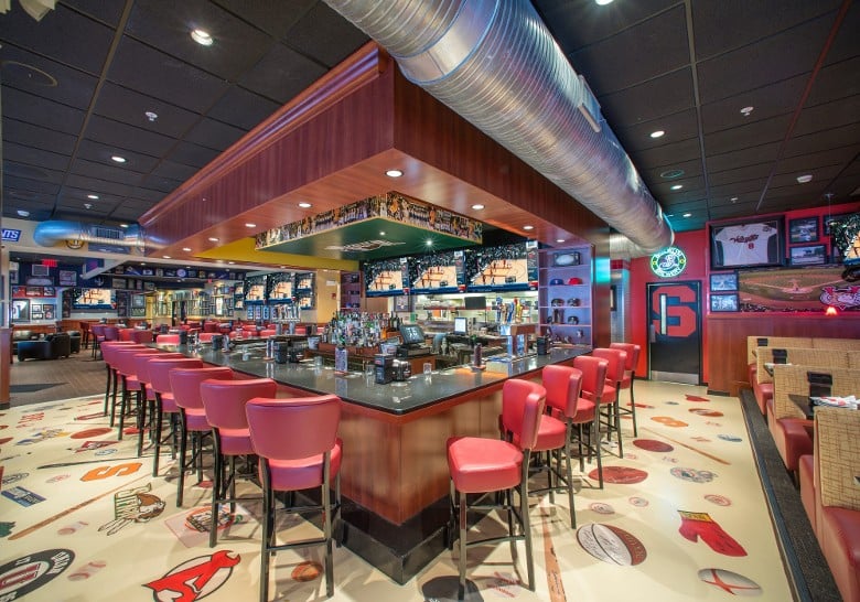 a square sports bar with red high top chairs