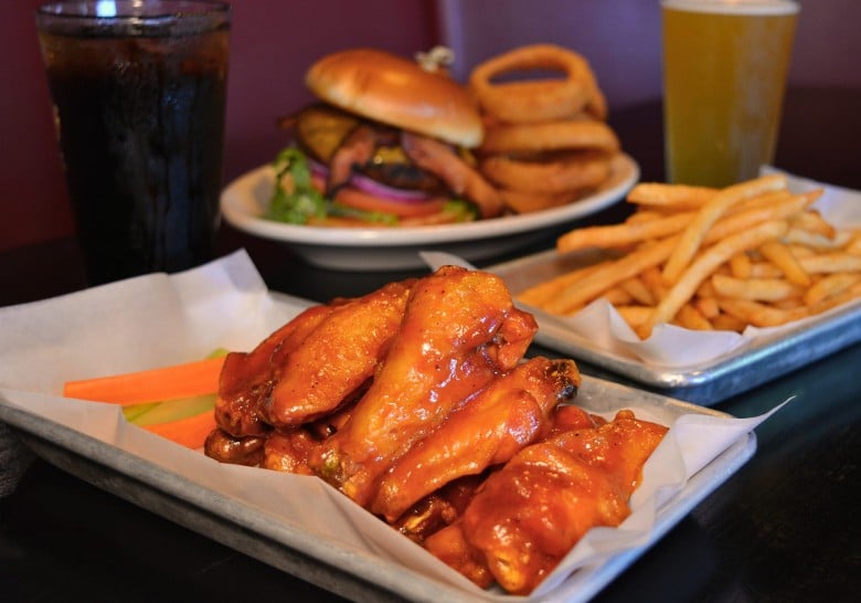 buffalo wings, french fries, and a burger with onion rings on a table