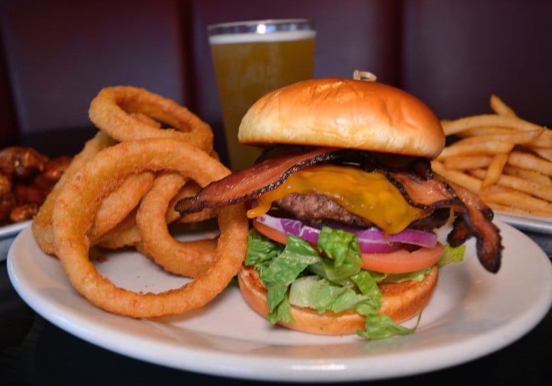 a burger with onion rings on a white plate