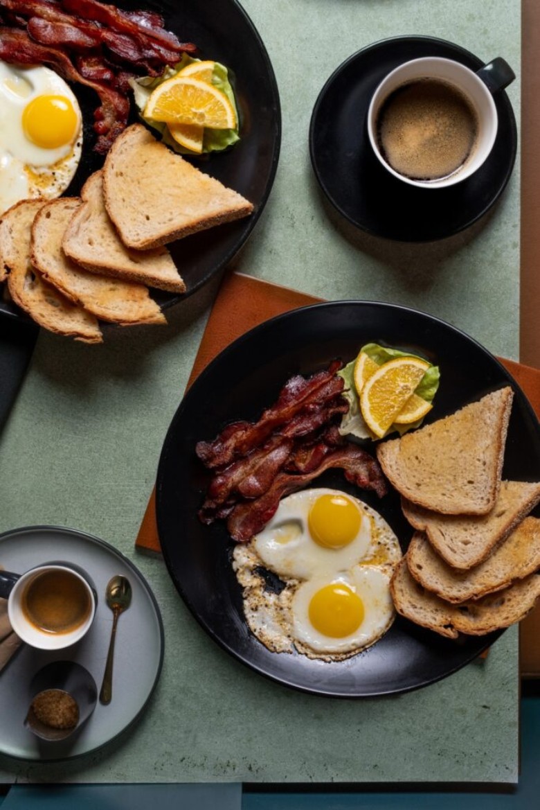 eggs, bacon and toast plates on a table