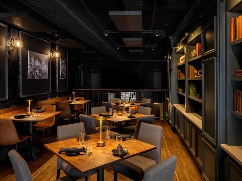 an upscale restaurant dining room with tables, and books on the walls