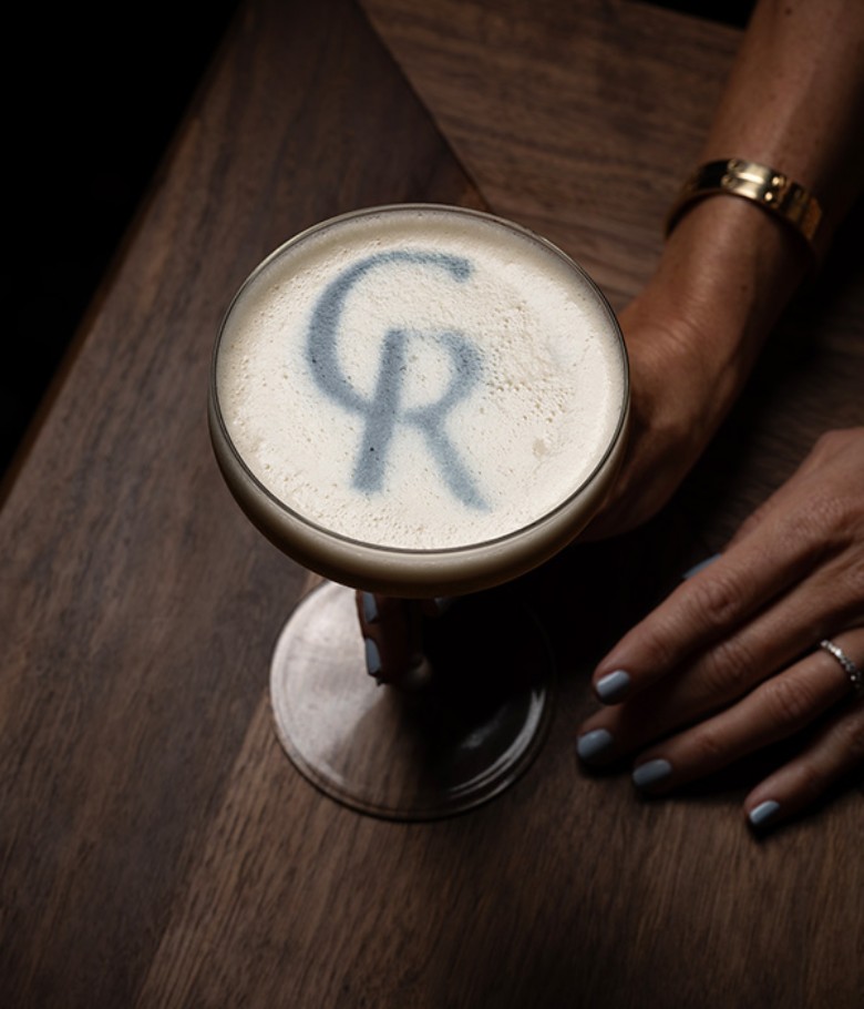 a cocktail with the letters C and R written in the foam