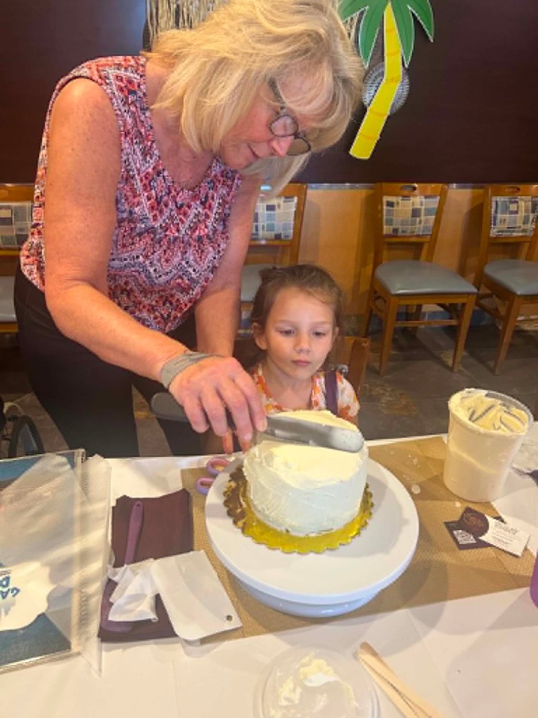 a woman putting buttercream on a cake while a girl watches