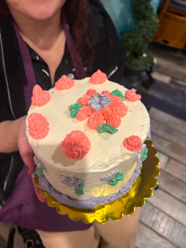 a person holding up a decorated buttercream cake