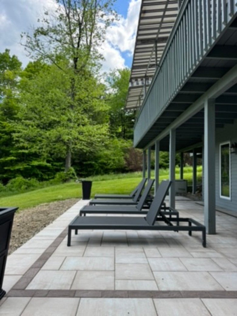 a stone patio outside of a house with lounge chairs