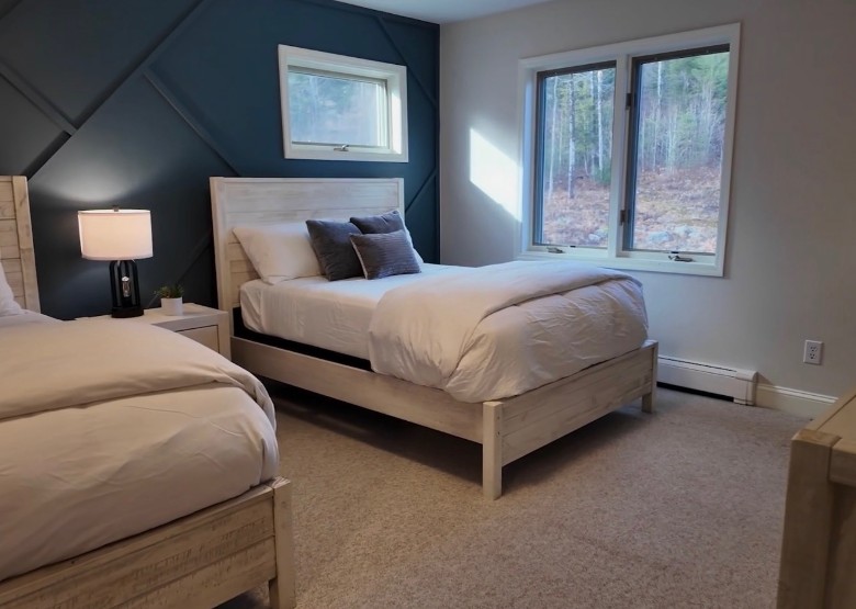 two beds in a bedroom with a large window and a smaller window