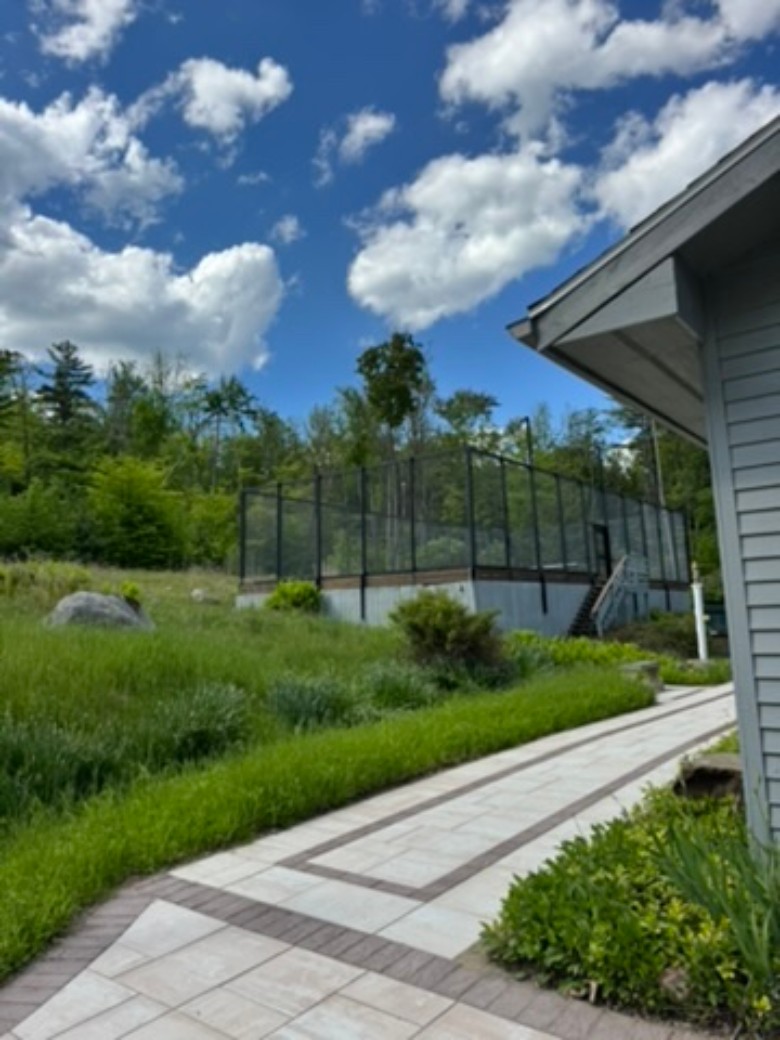 a stone walkway along the side of a dark gray house