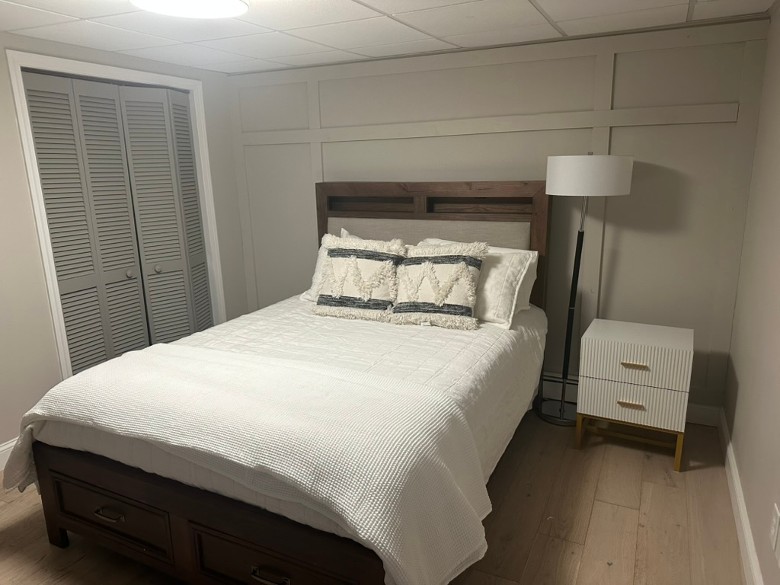 a bedroom with a bed, a lamp, a small cabinet, and a closet