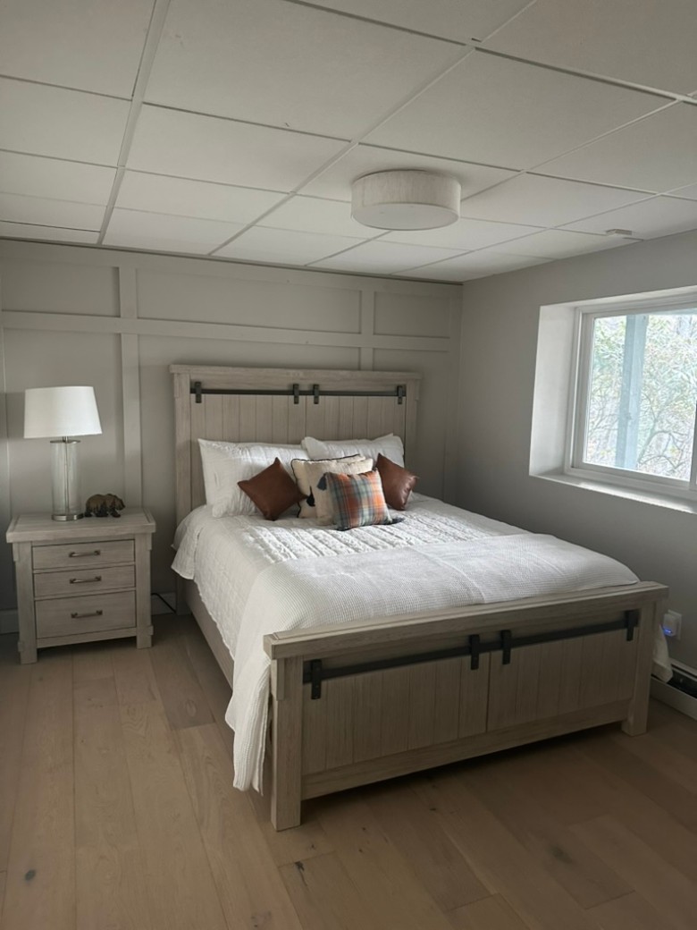 a bedroom with a bed, a dresses and lamp, and a window to the side