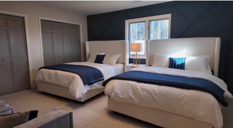 a bedroom with two beds, two closets, and windows between the beds