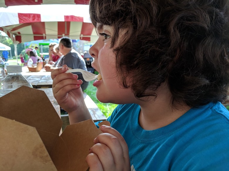 a kid eating from a brown takeout container