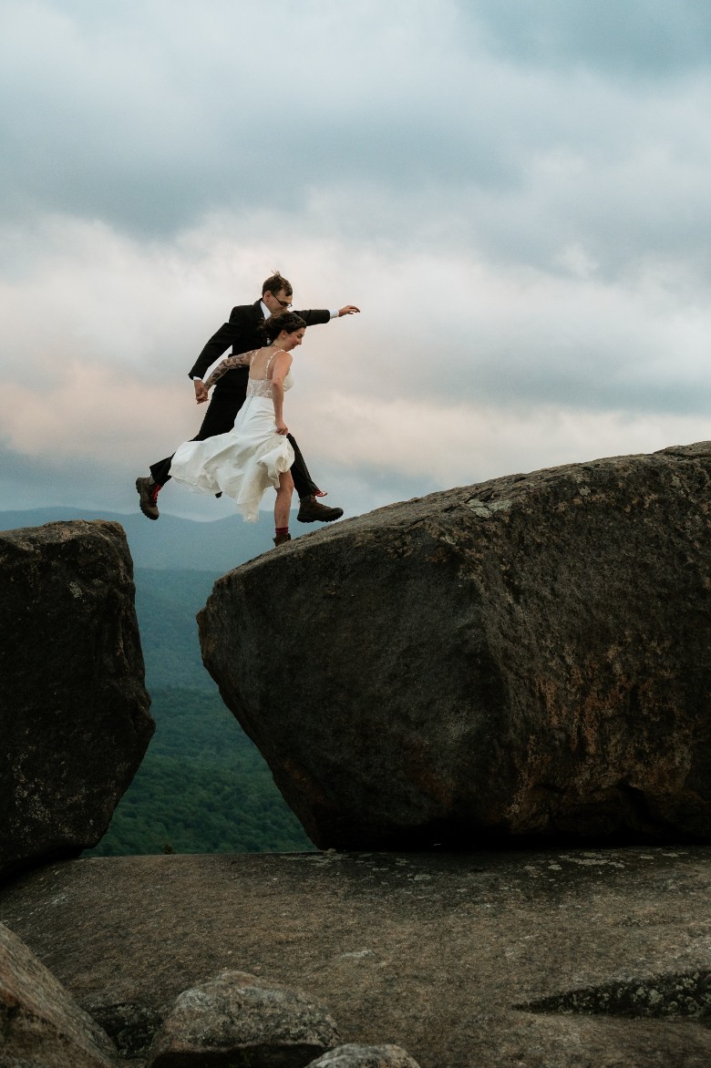 wedding couple leaping from one boulder to another