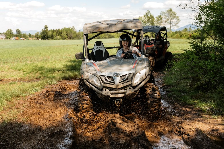 couple in separate ATVs going through mud