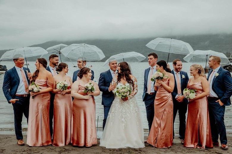 wedding party with umbrellas by a lake