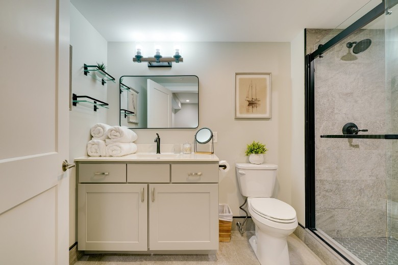 a bathroom in a house with a sink, mirror, toilet, and glass shower