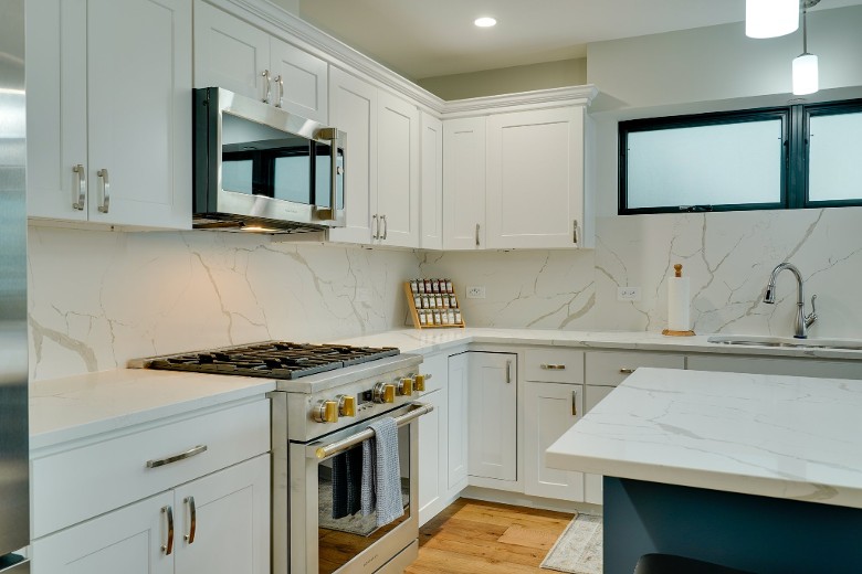 a modern kitchen with white cabinets, an oven, and a microwave