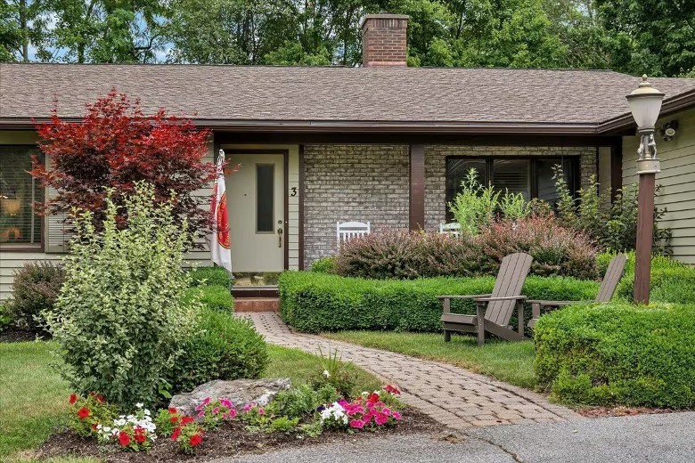 the front of a house with some shrubs and hedges along the walkway