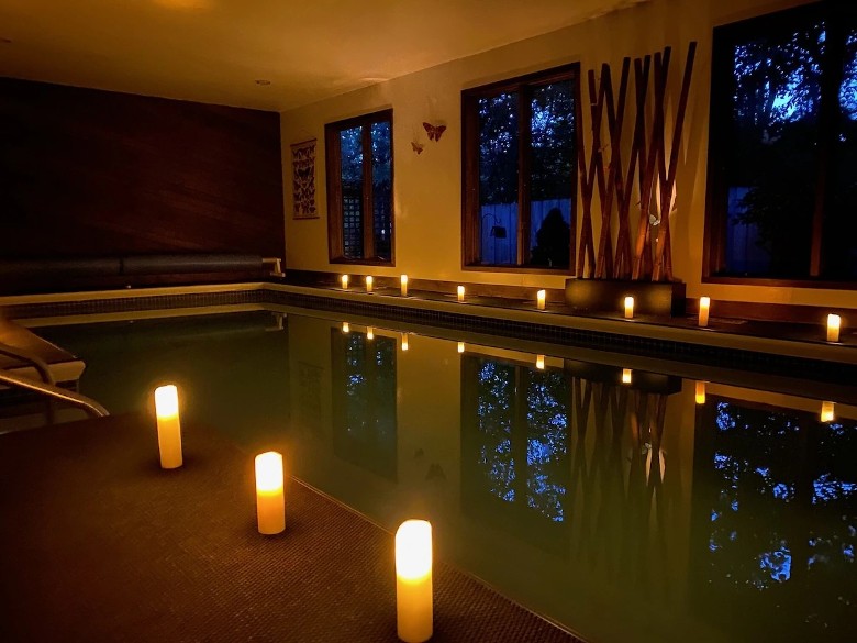 a swimming pool and windows inside of a house room, with candles on