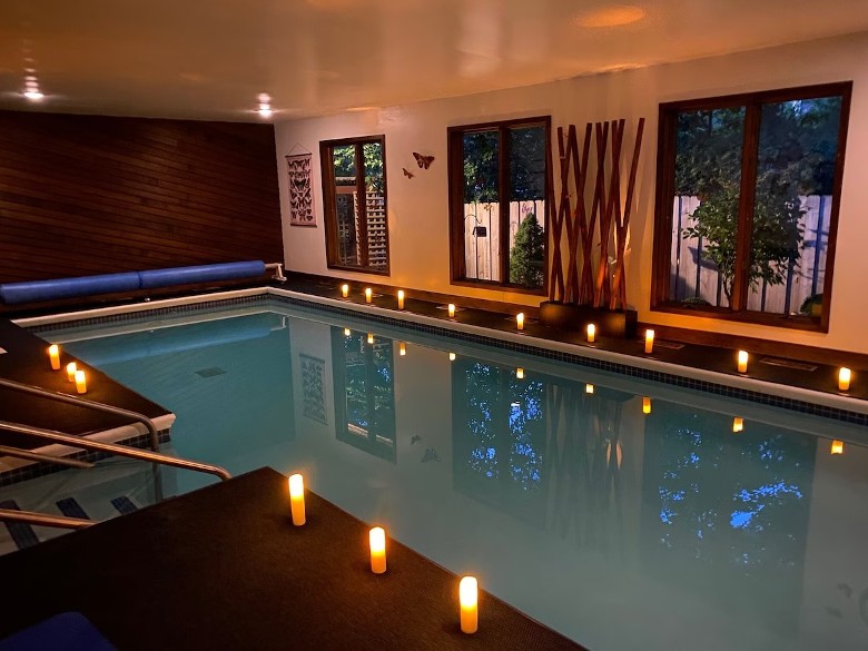 a swimming pool and windows inside of a house room, with candles on