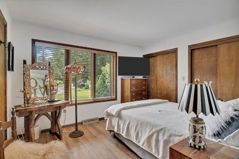 a bedroom with a TV, mirror, windows, and lamp
