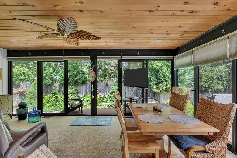 a sun room with large windows and a dining table