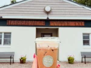 a person holding up an iced coffee in front of a coffee shop