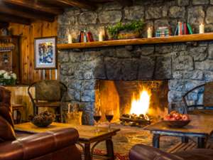 roaring fire in large fieldstone fireplace in seating area