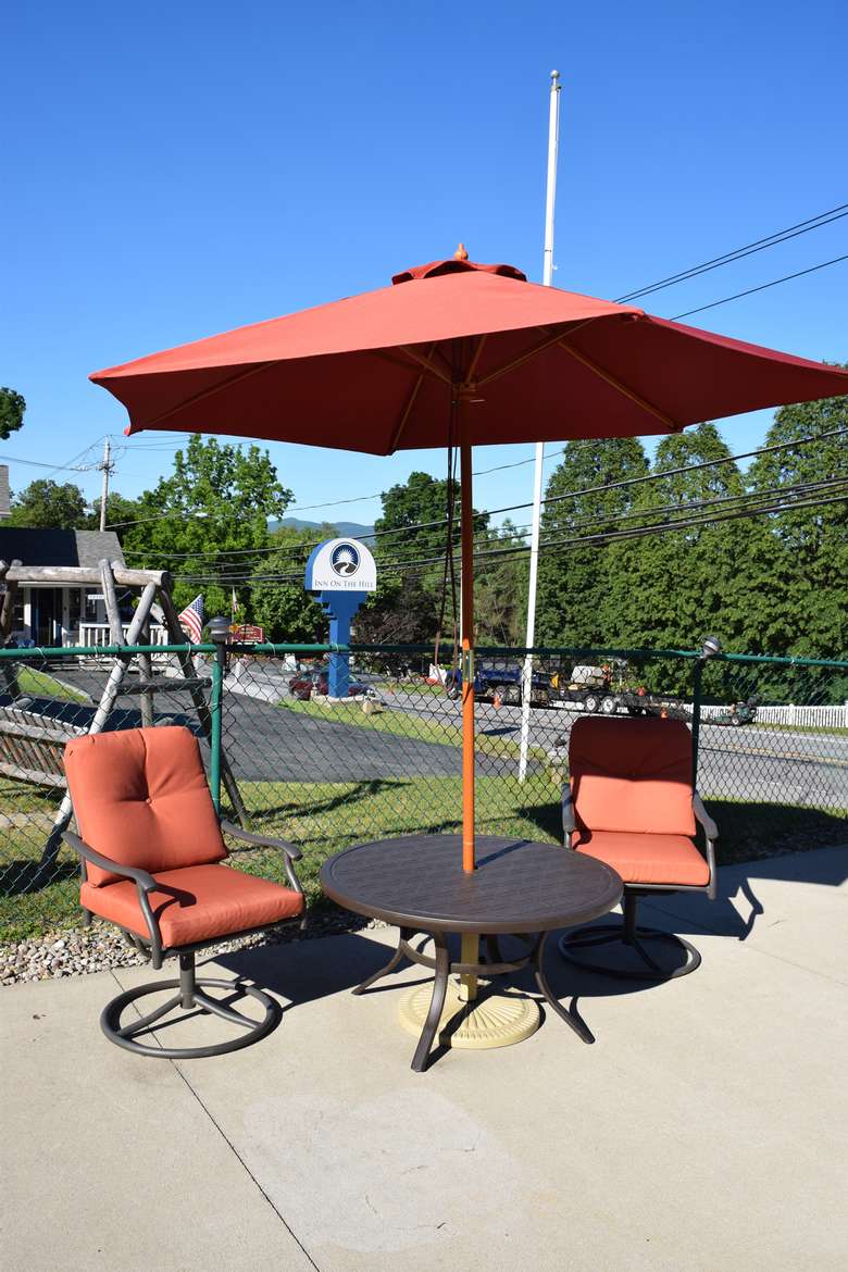 two chairs and a patio table with red umbrella