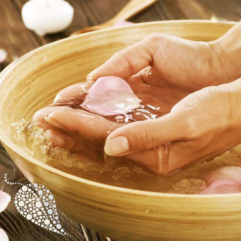 hands cupping a floral petal in a water bowl