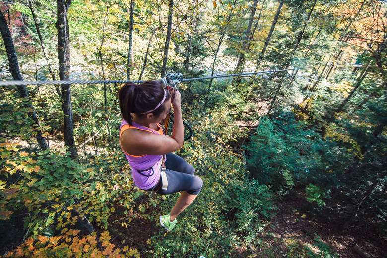 Woman ziplining through Westwood Forest at Adirondack Extreme