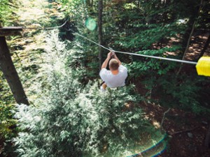 Man zip lining over Alder Brook at Adirondack Extreme Adventure Course