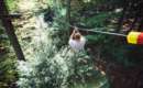 Man zip lining over Alder Brook at Adirondack Extreme Adventure Course