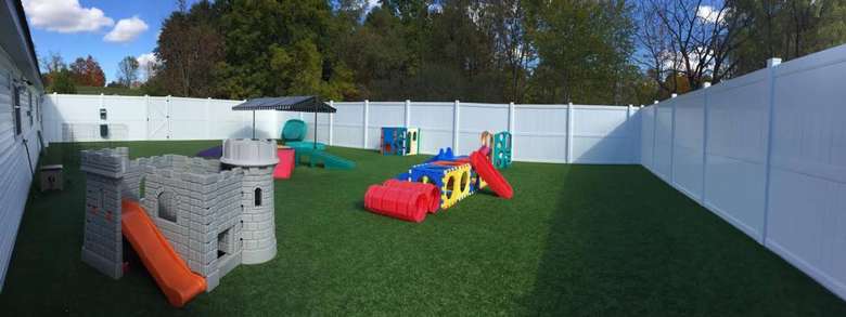 doggie play area with obstacles, artificial turf, and a tall white fence